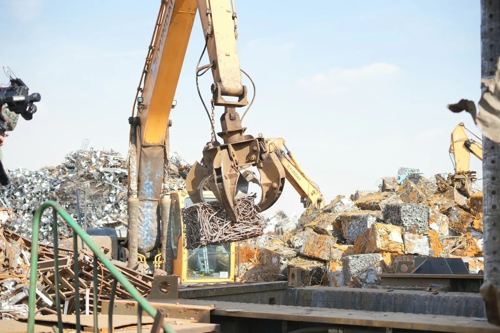 Excavator grab sorting scrap metal in a processing yard